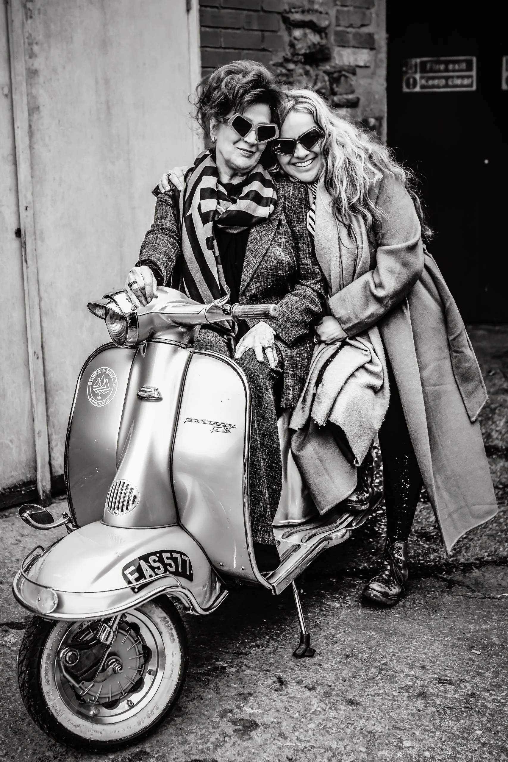 Anna Lewis and her mum Rose in Ffin MOD sunglasses sharing a vintage scooter, black and white