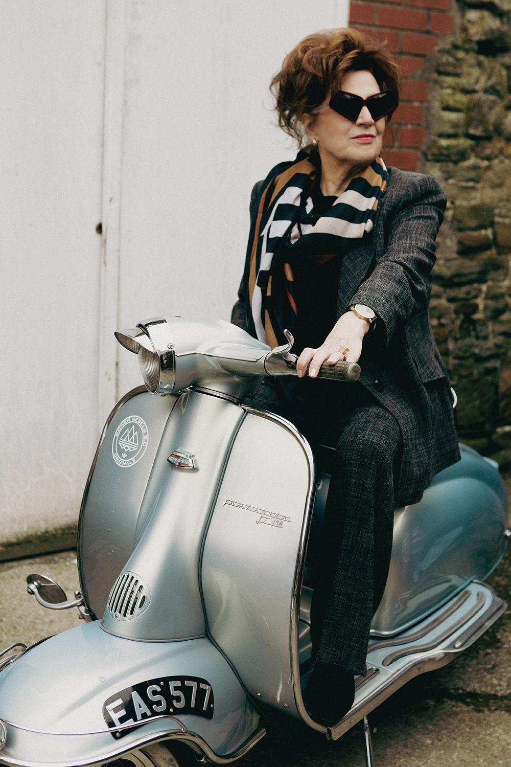 Rose, Anna's mum, in black Ffin MOD sunglasses and a scarf riding a silver vintage scooter