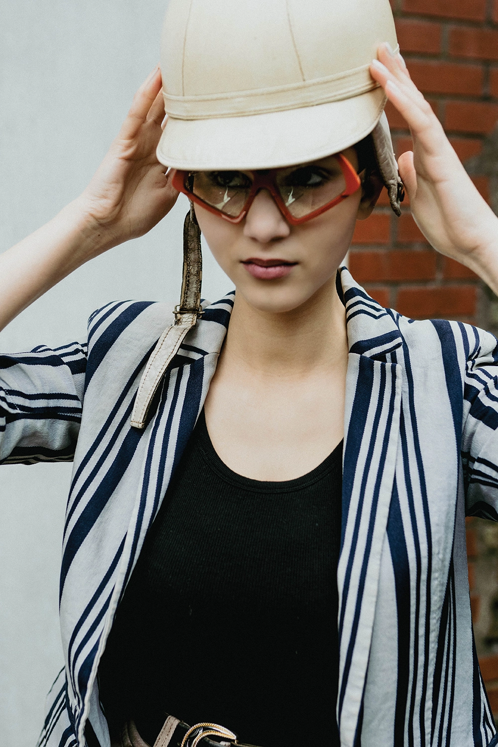 Model in a cream helmet and red-tinted Ffin MOD sunglasses, striped blazer