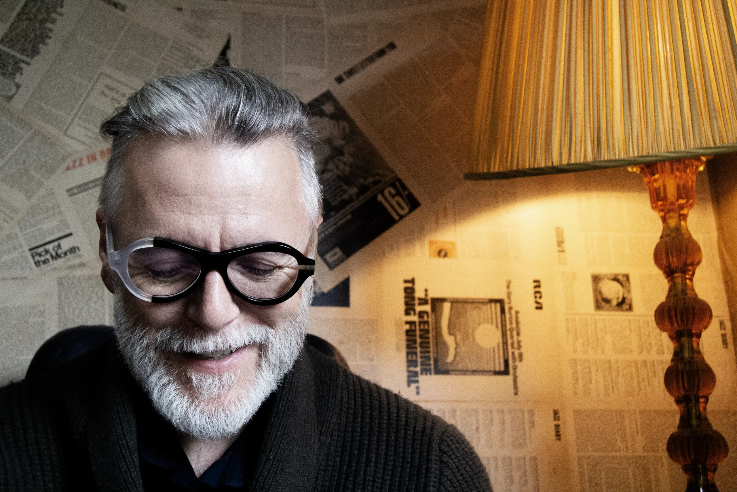 Smiling Steve Balsamo in round black Ffin ANA award-winning optical frames beside a glowing lamp