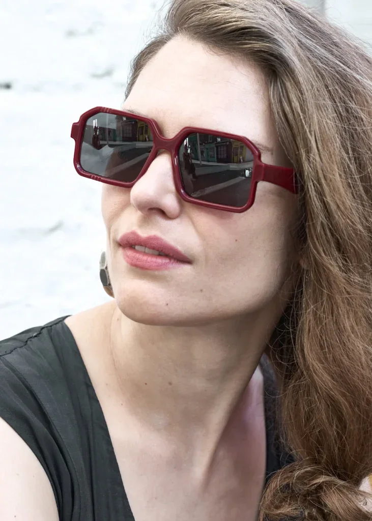 Woman in square red Ffin BOD designer sunglasses, looking to one side