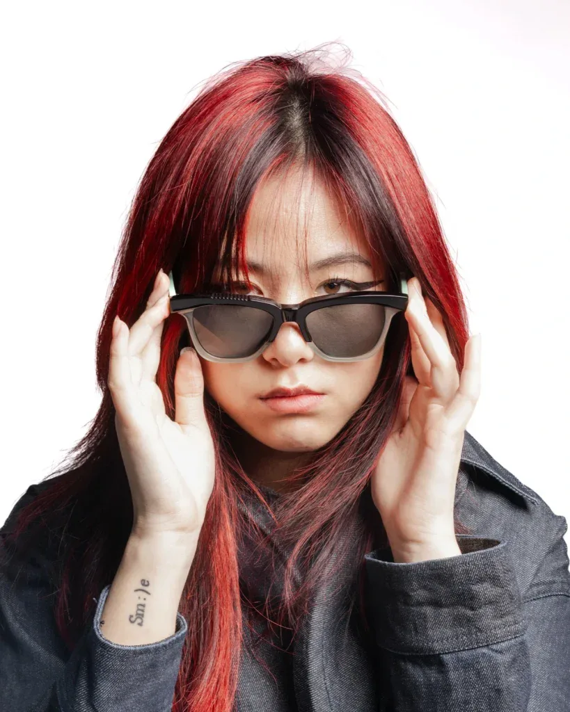 Woman with long red hair adjusting black Ffin GEN designer sunglasses with mint temples