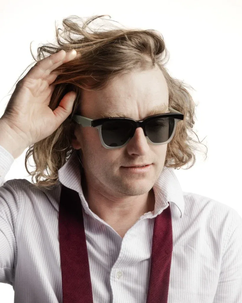 Man with tousled blond hair in black Ffin GEN designer sunglasses with mint temples