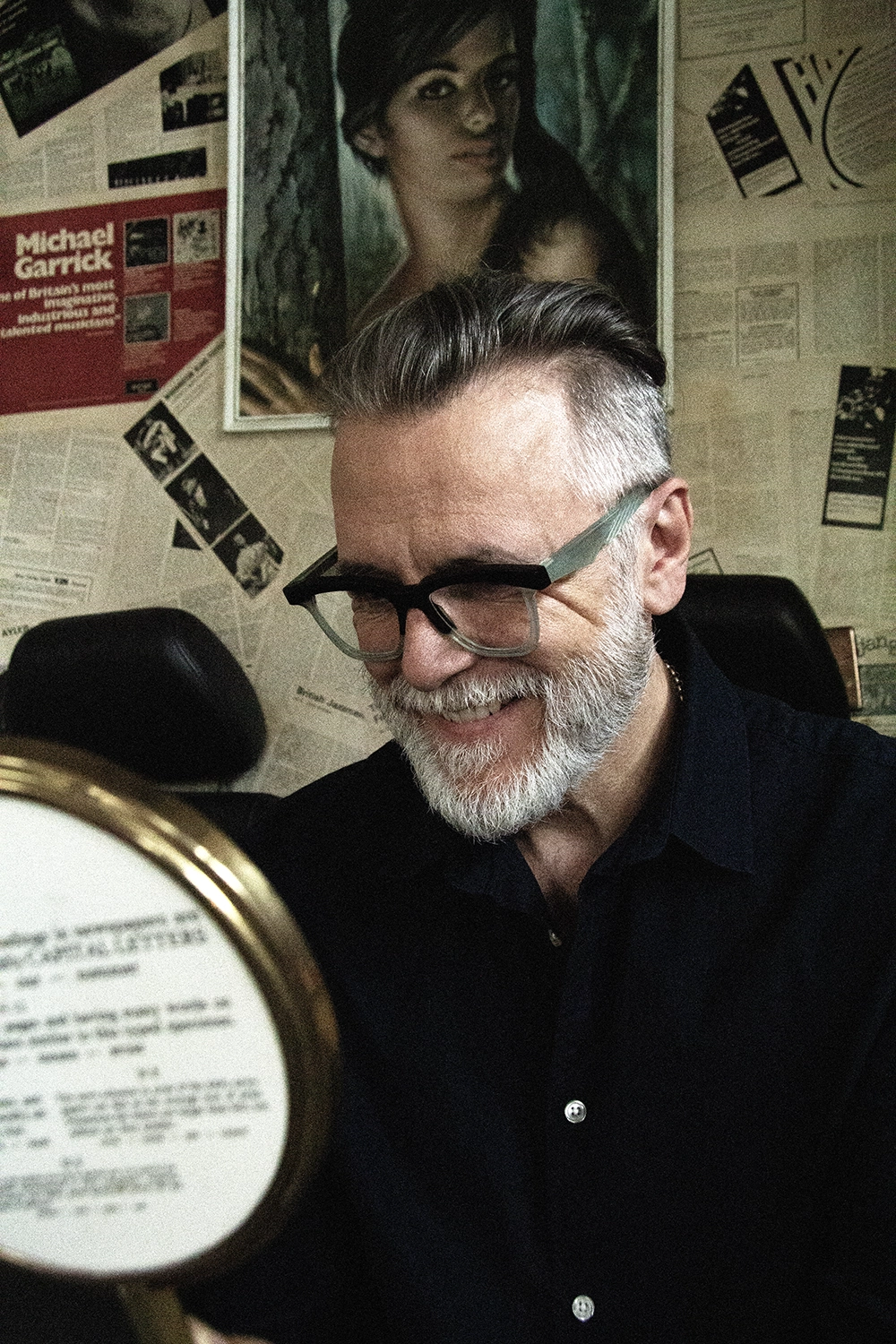 Smiling Steve Balsamo in black Ffin GEN optical frames with mint temples, beside a hand mirror