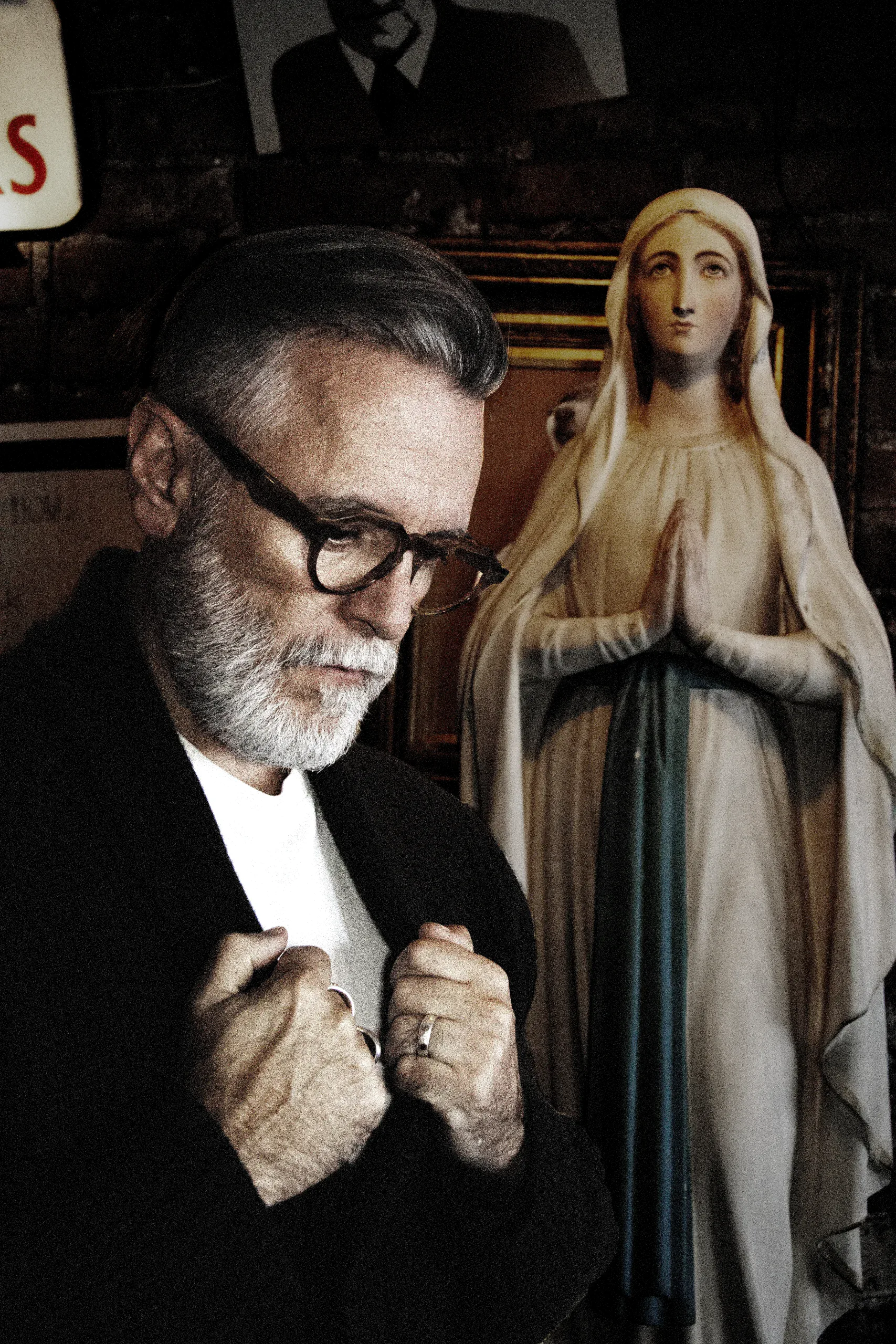 Steve Balsamo in round wood-effect Ffin NON optical frames beside a statue of the Virgin Mary