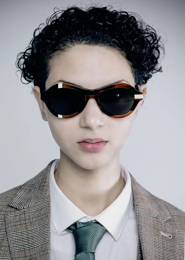 Woman in a tweed blazer and tie wearing black and tortoiseshell Ffin ANA award-winning designer sunglasses