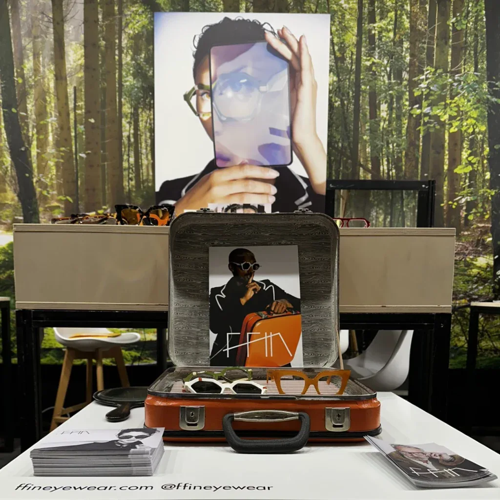 Ffin stand at MIDO with a vintage suitcase display and brochures beneath a model portrait
