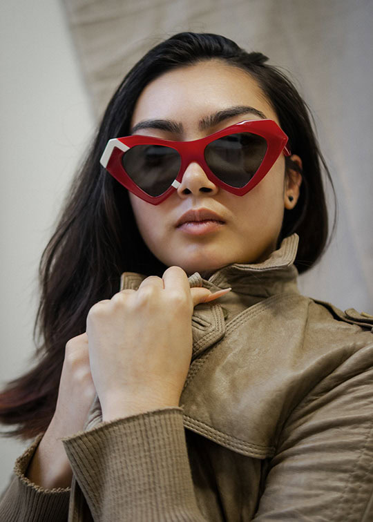 Woman in red heart-shaped Ffin NOS designer sunglasses and a khaki jacket