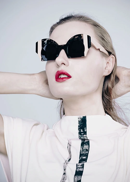 Woman with red lipstick in black butterfly Ffin ORA designer sunglasses, hands behind her head