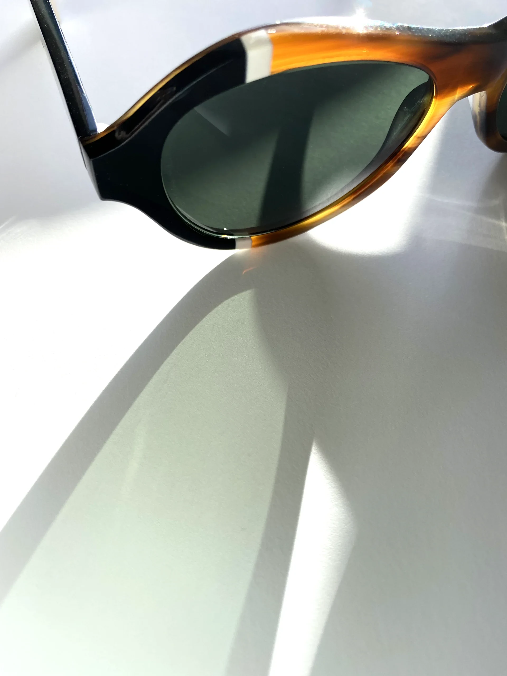 Ffin ANA tortoiseshell sunglasses with a green lens in soft light, close-up