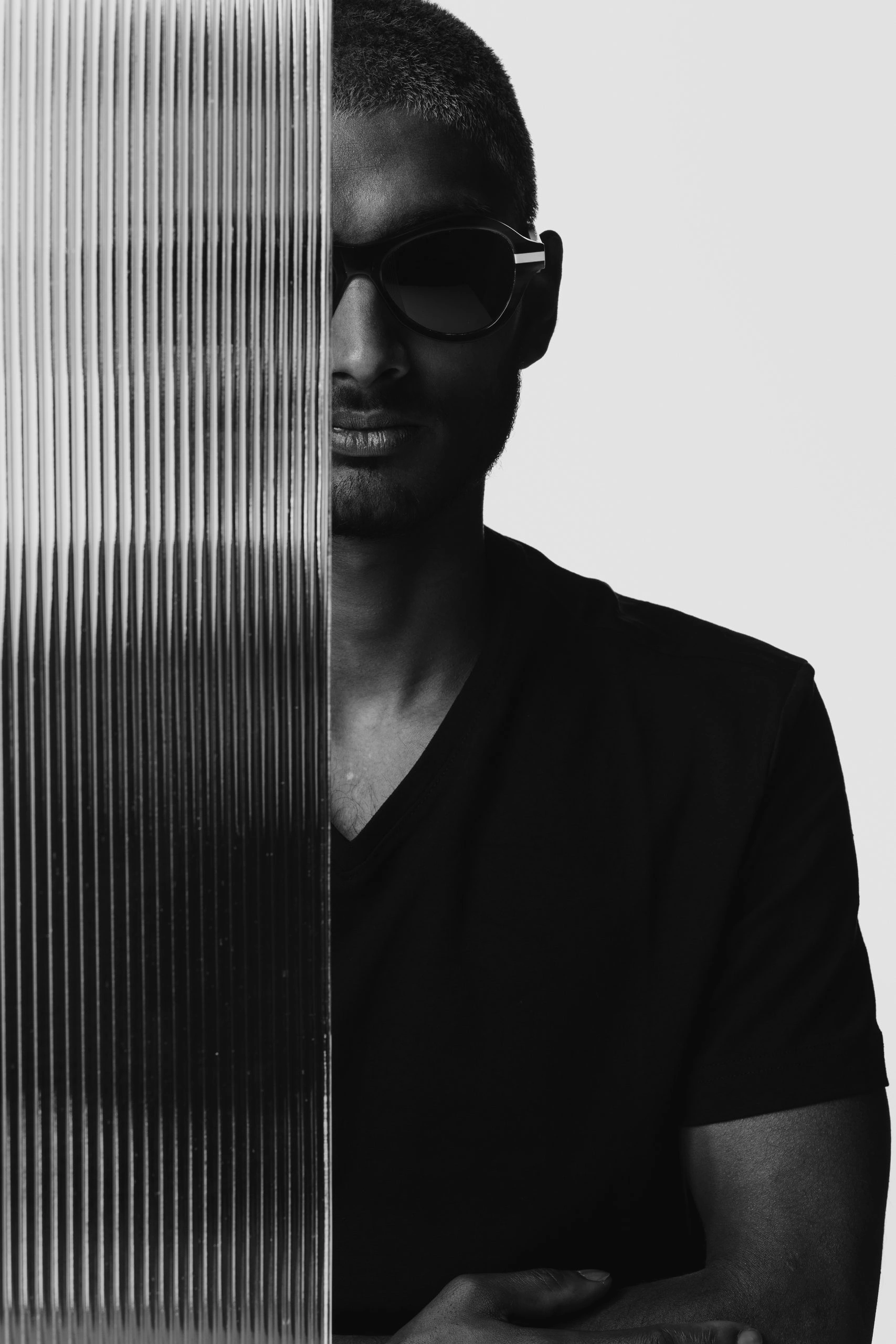 Black and white portrait of a man half hidden behind ribbed glass in Ffin ANA award-winning sunglasses