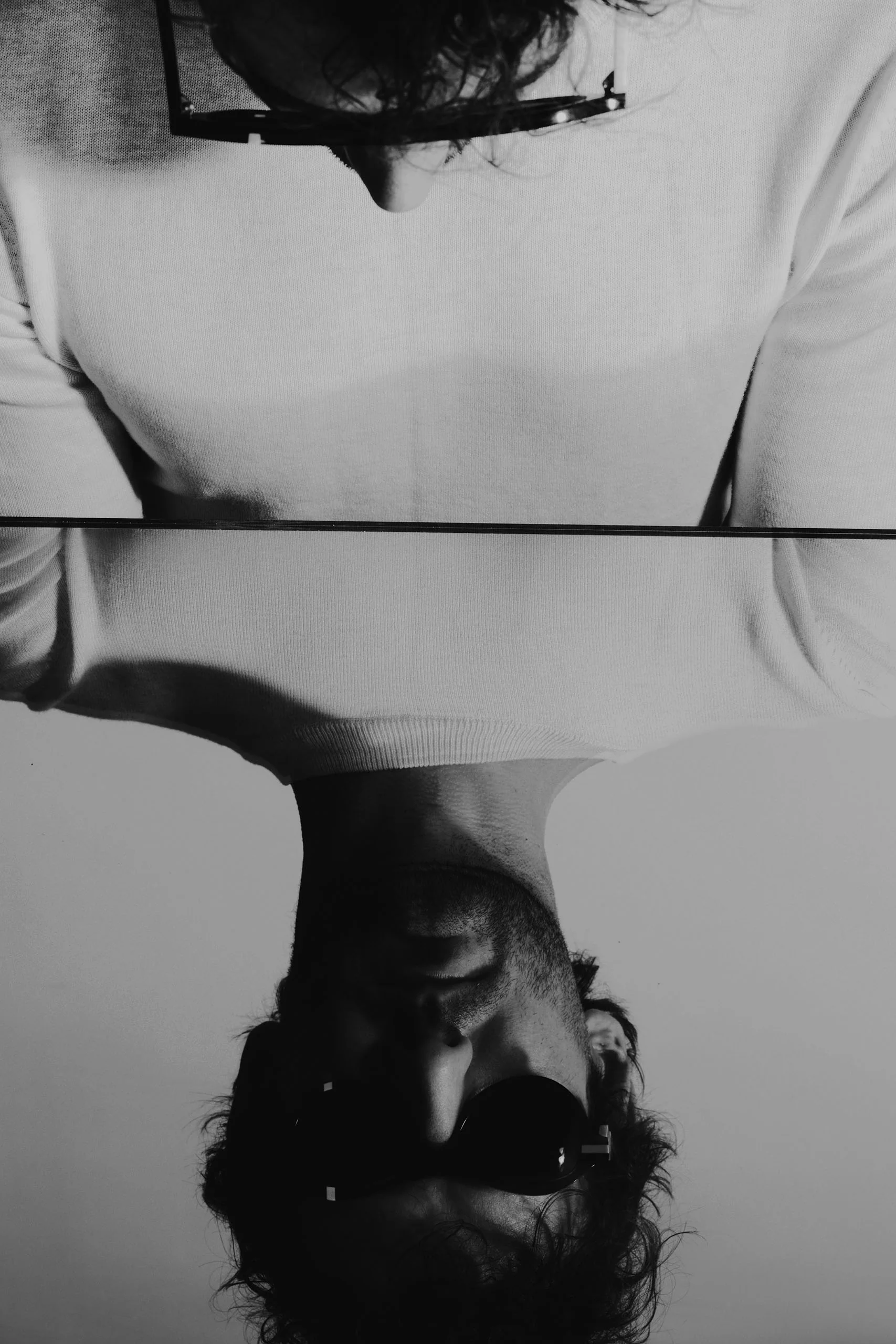 Man in Ffin ANA sunglasses with his reflection inverted in a mirror, black and white