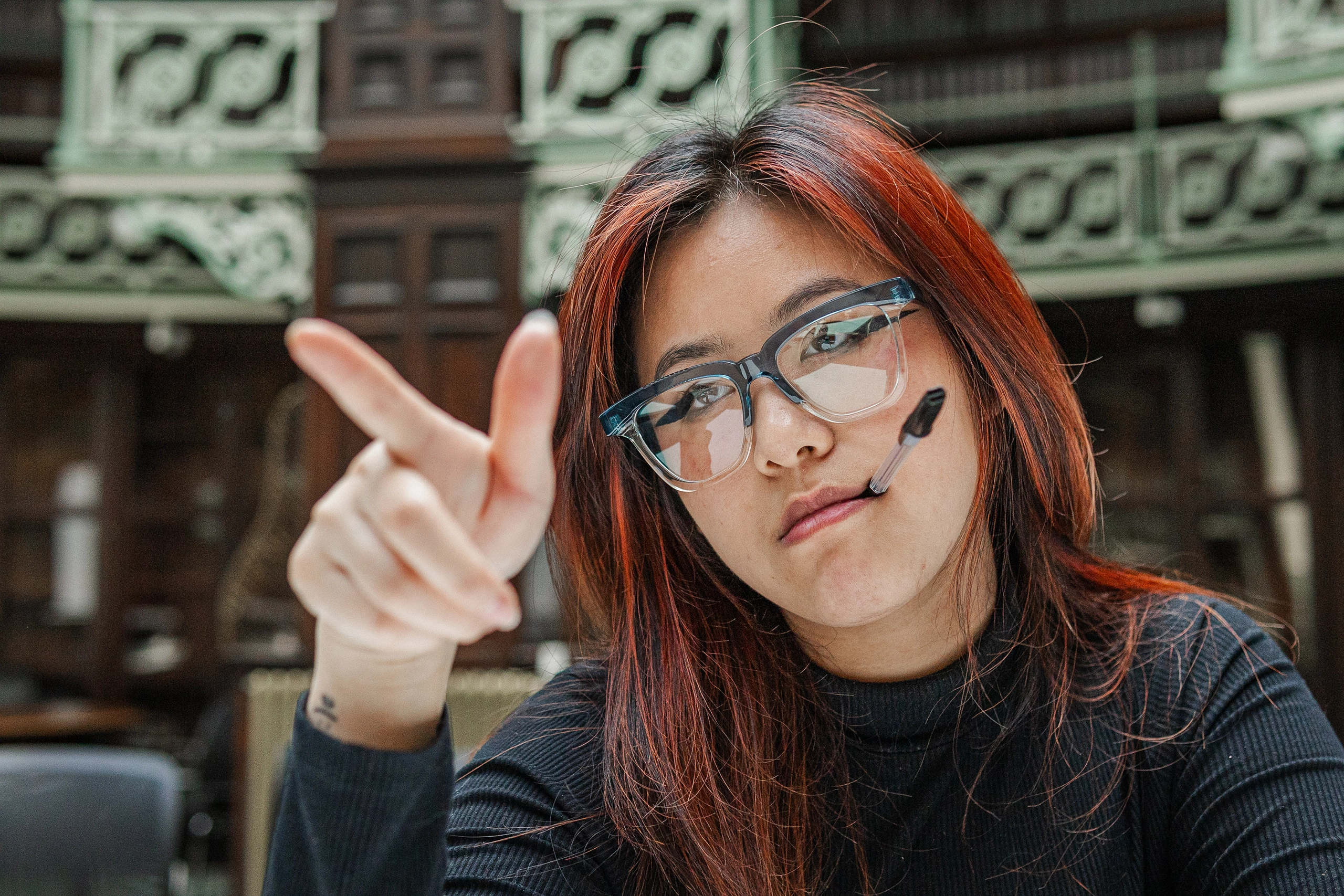 Woman with red-brown hair pointing playfully at the camera in blue Ffin GEN optical frames