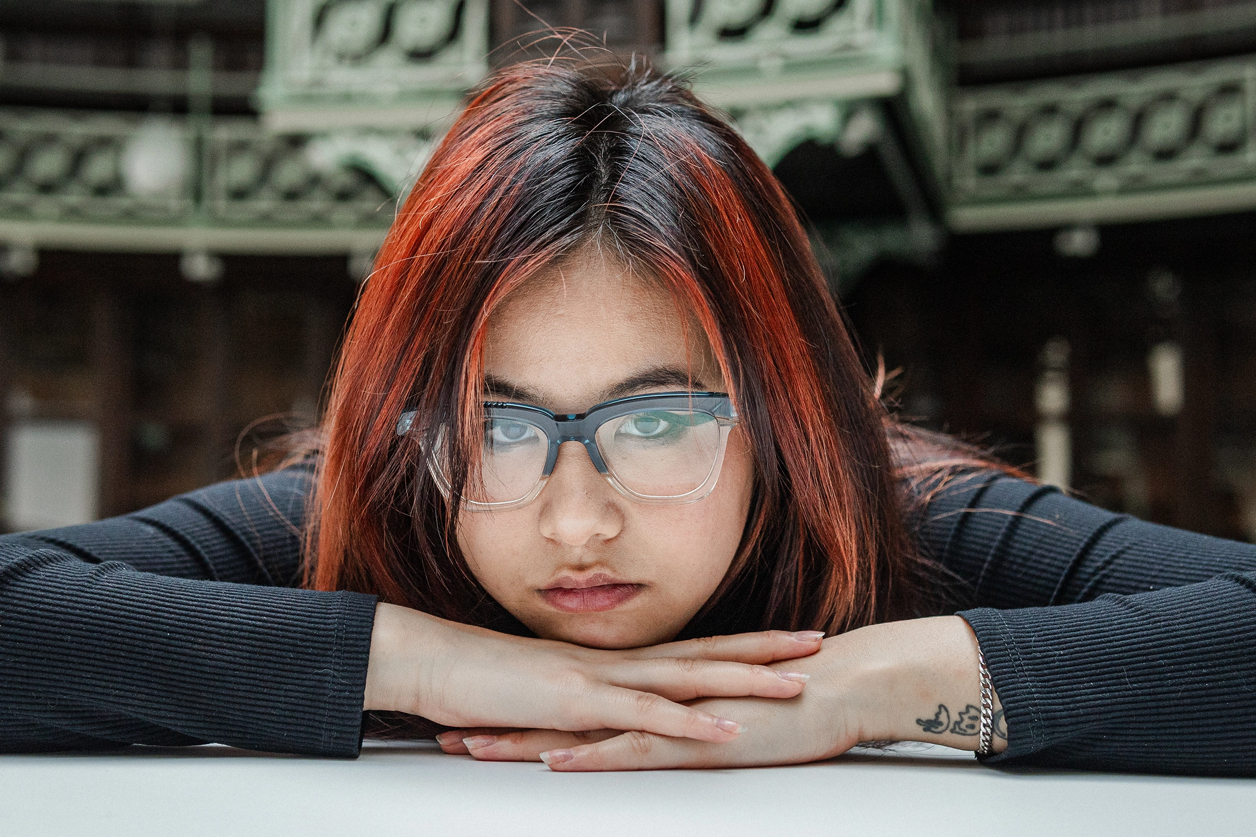 Woman with red-brown hair resting her chin on her arms in blue Ffin GEN optical frames