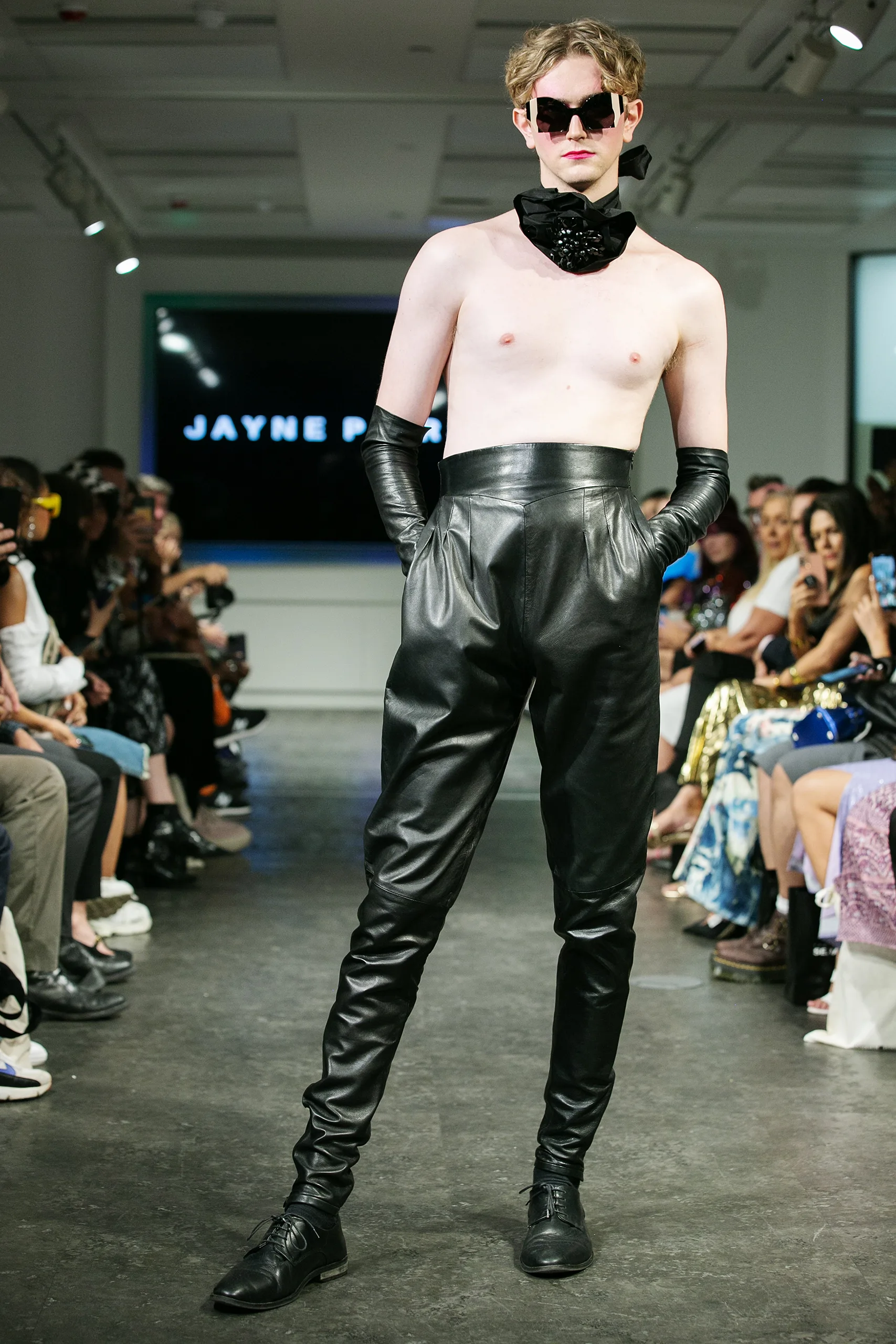 Model in high-waisted leather trousers and gloves on the Jayne Pierson catwalk in Ffin ORA sunglasses