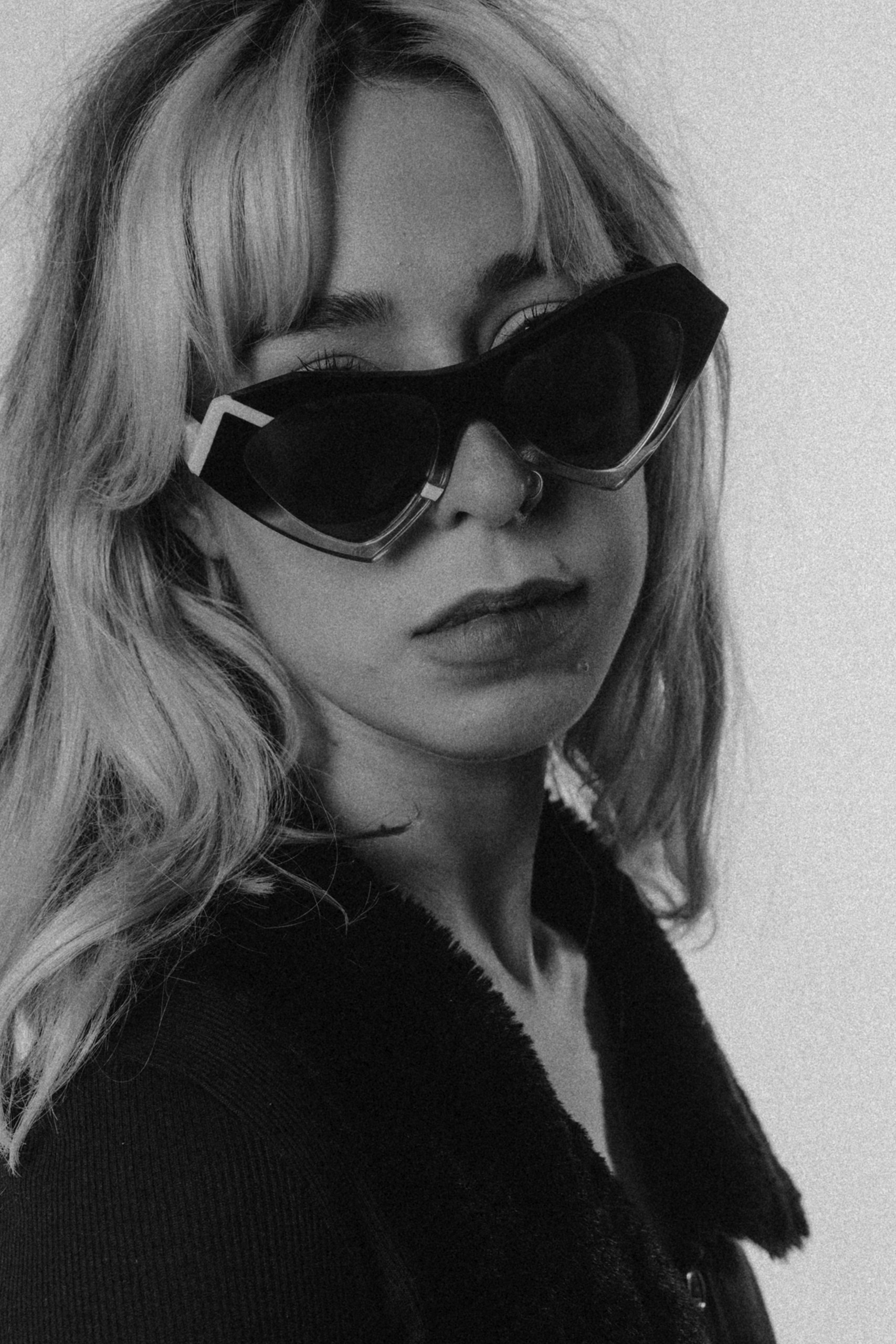 Woman with wavy blond hair in black heart-shaped Ffin NOS designer sunglasses