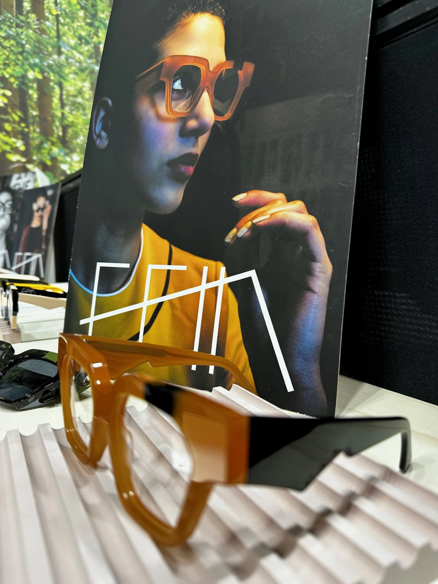 Orange Ffin AMO optical frames on display before a portrait print at the Ffin stand at MIDO
