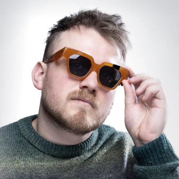 Bearded man in orange square Ffin AMO optical frames, holding the temple