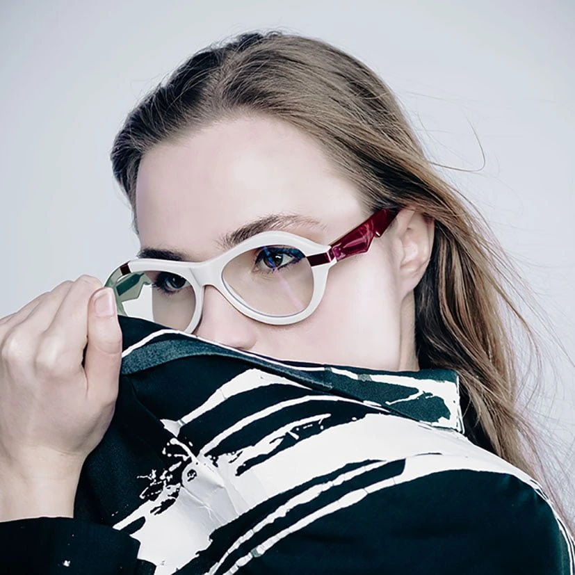 Woman in white and burgundy Ffin ANA award-winning optical frames, pulling up a monochrome print collar
