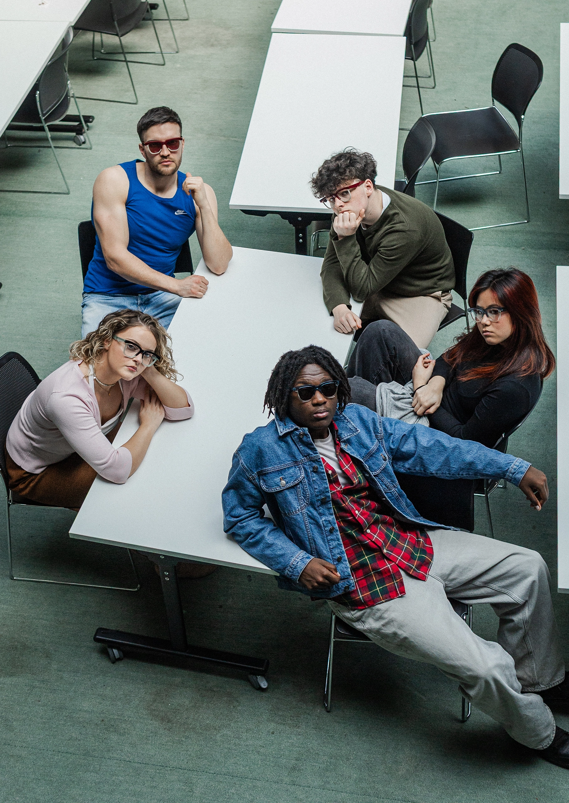 High-angle view of five models in Ffin GEN eyewear around library tables, Breakfast Club shoot