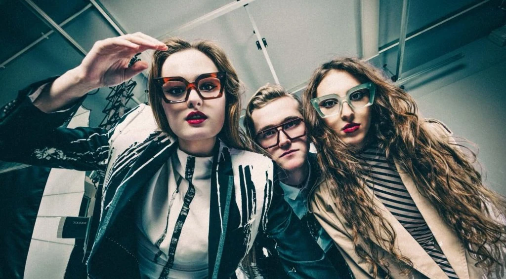 Three models in Ffin optical frames leaning into a wide-angle shot, wearing monochrome print jackets