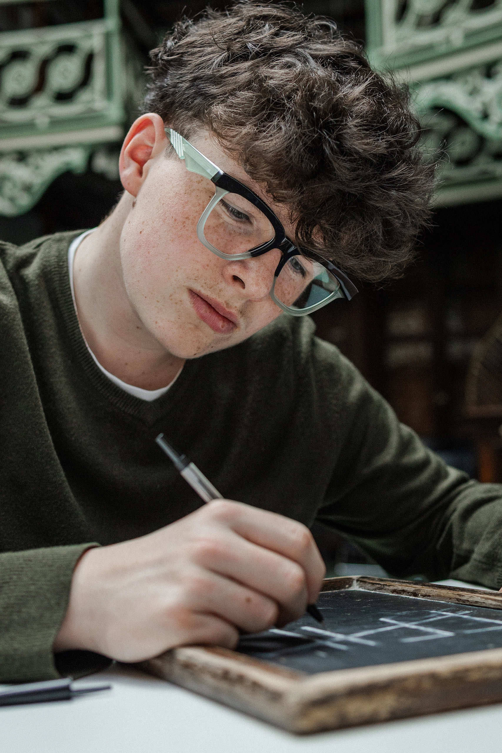 Young man writing on a chalkboard in black Ffin GEN optical frames