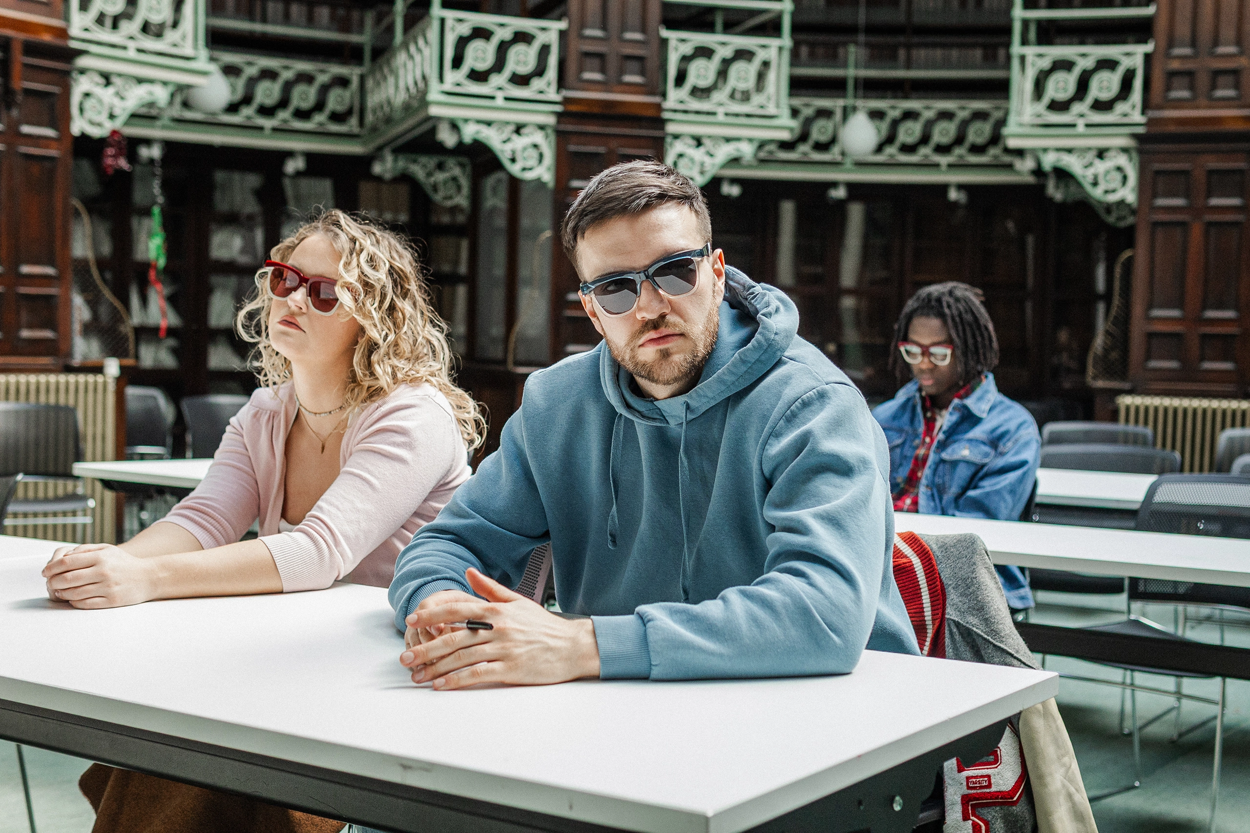 Three models seated at a library table in Ffin GEN designer sunglasses, a Breakfast Club homage