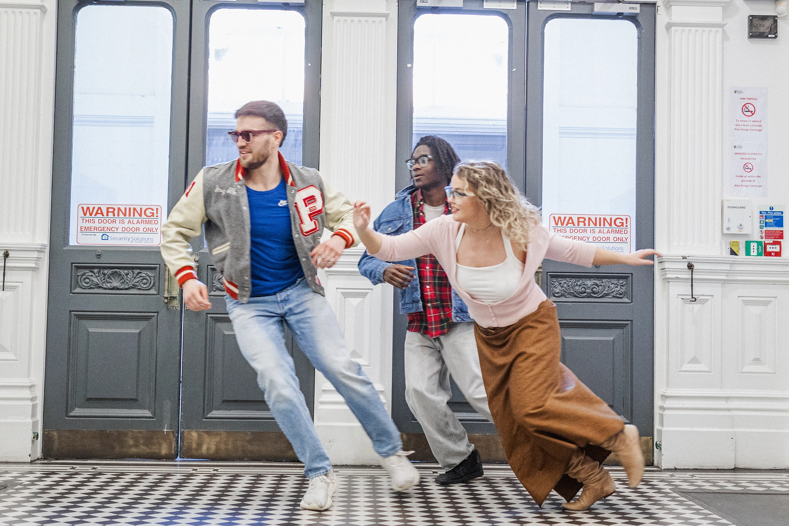 Models running across a tiled hallway in Ffin GEN eyewear, a Breakfast Club homage