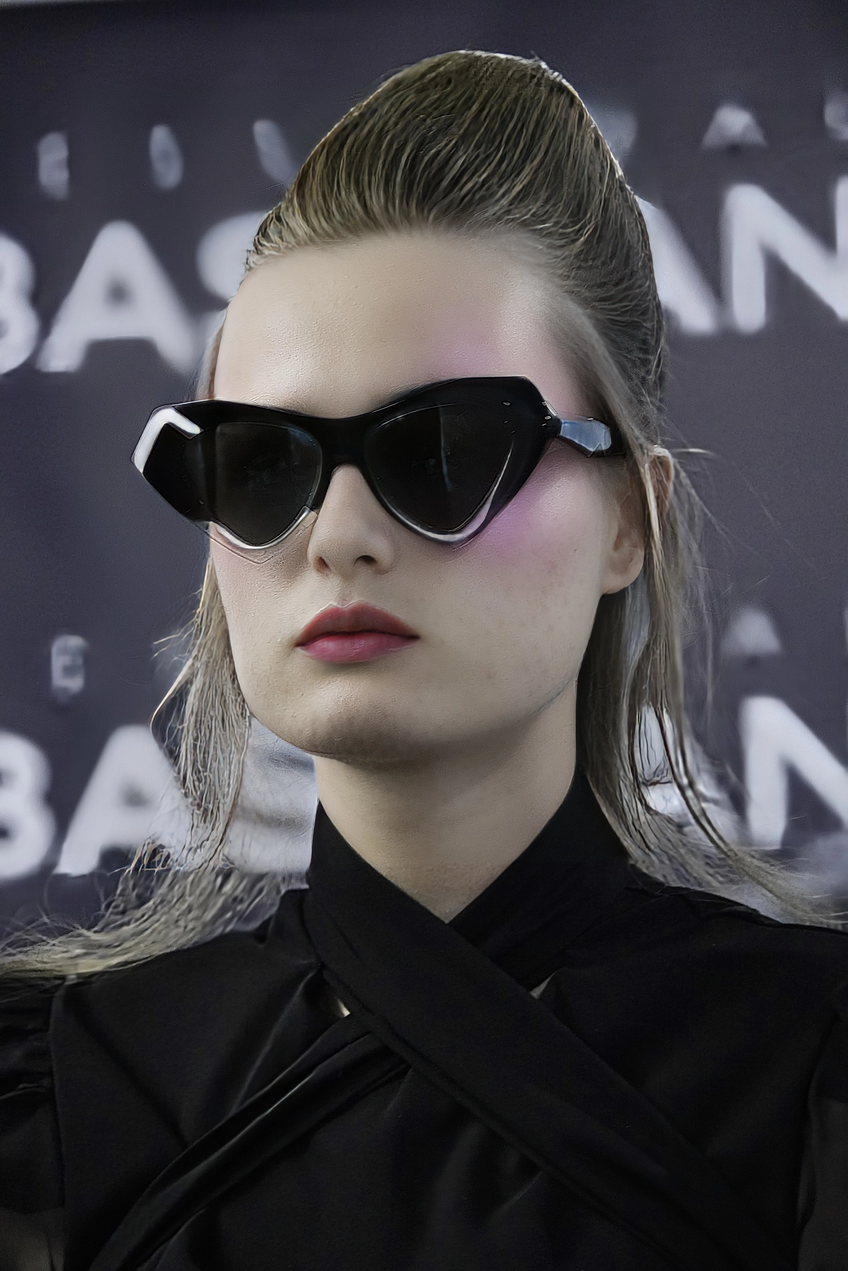 Model with slicked-back hair in black angular Ffin designer sunglasses backstage at London Fashion Week