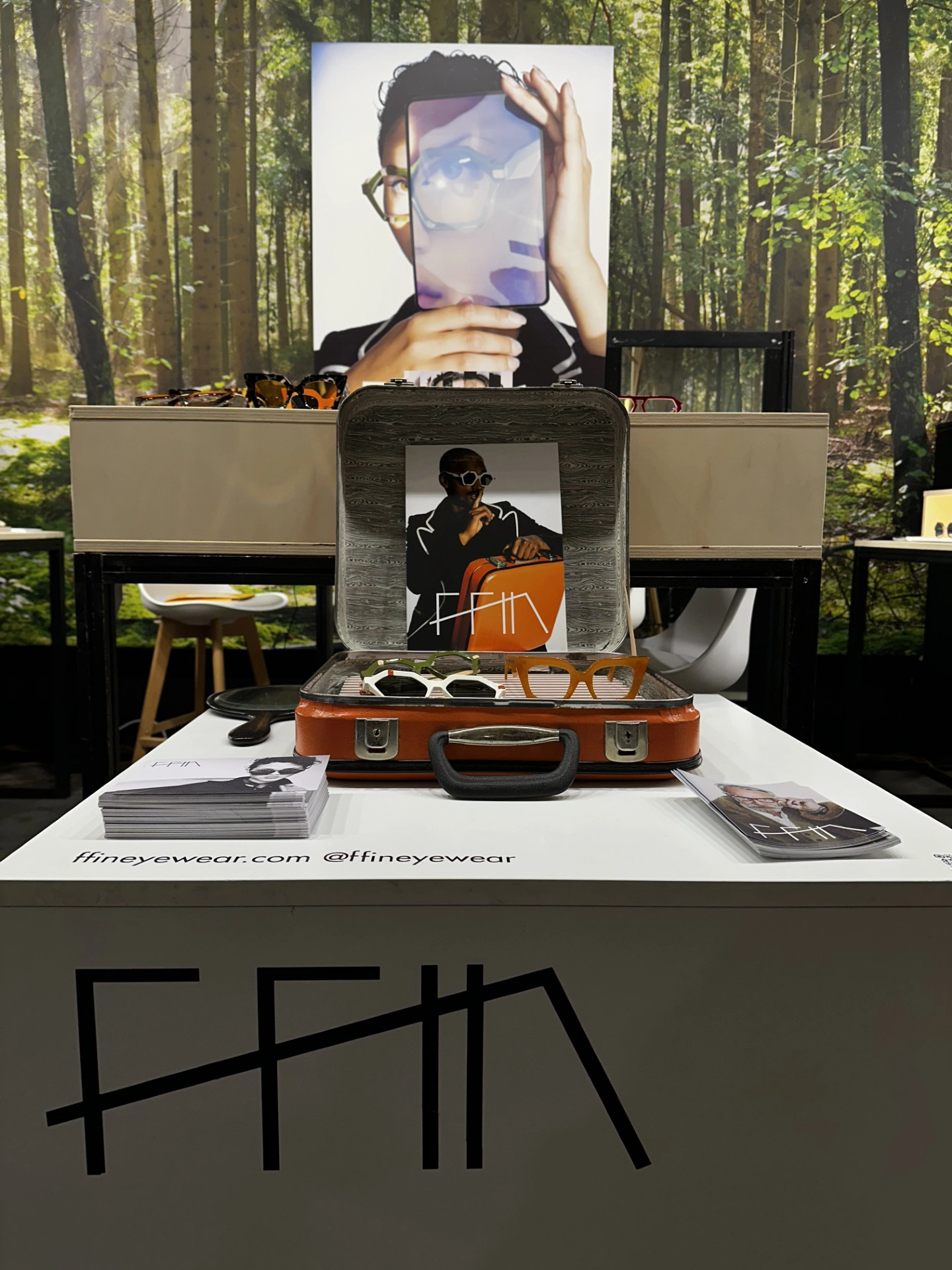 Ffin stand at MIDO with a vintage suitcase display before a woodland backdrop