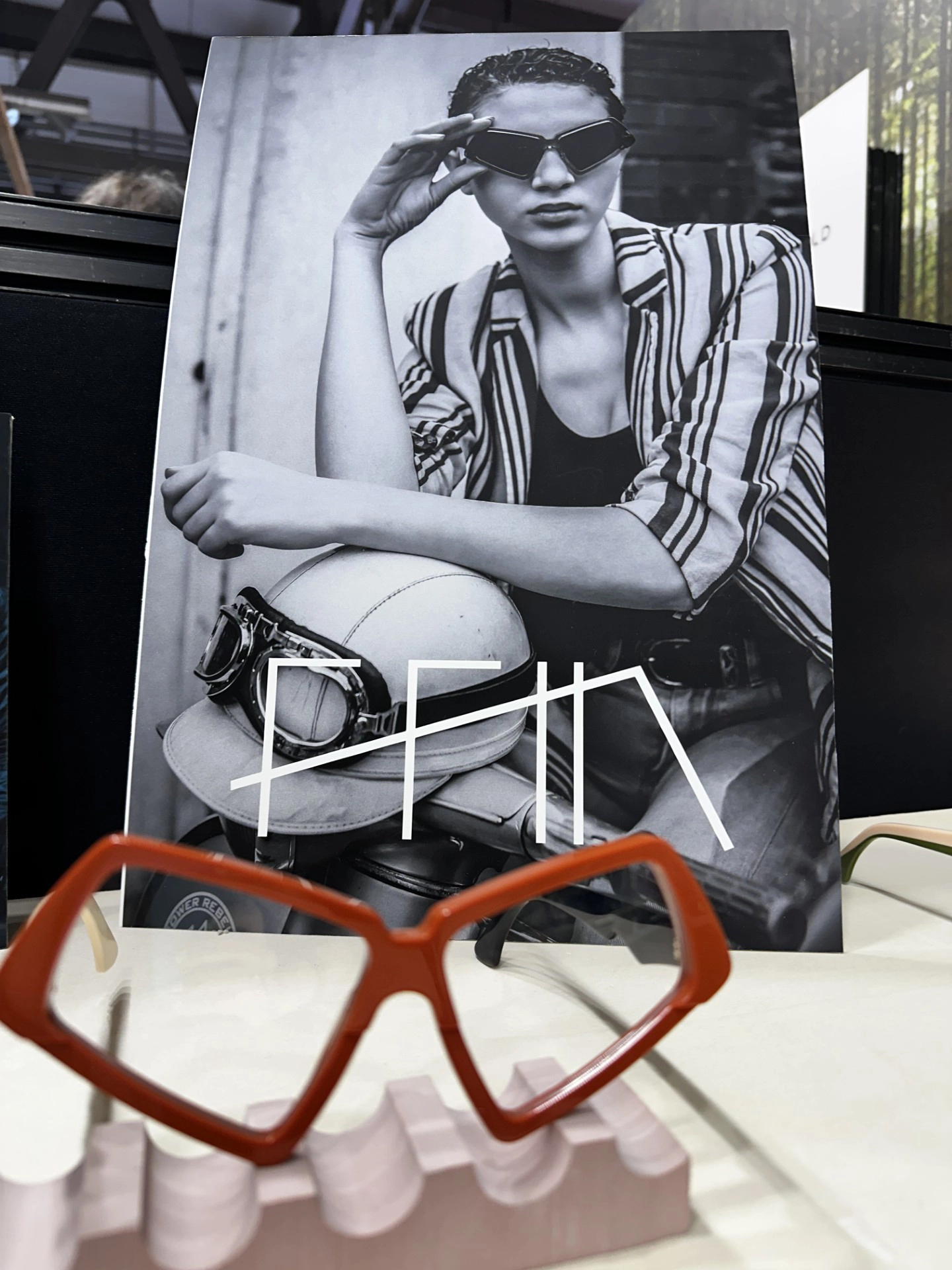Orange angular Ffin MOD frames on display before a black and white portrait print at MIDO