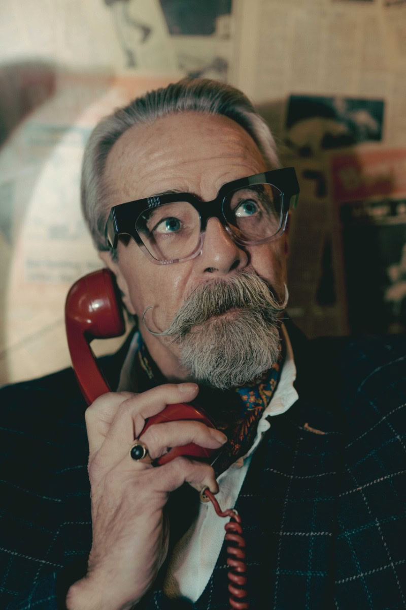 Gary in bold black Ffin optical frames holding a red vintage telephone